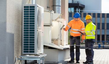 Two technicians performing an Air Conditioning Service for a commercial building in Quogue, NY
